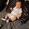 baby, bed, black_and_white_shoes, blanket, casual_wear, child, curious, cute, furniture, indoors, infant, person, pillow, portrait, resting, romper, shoes, striped_clothing, striped_pillow, young_child