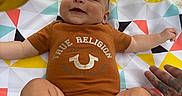 Ryatt joined the competition — help win amazing prizes! baby, babywear, child, clothing, colorful, cute, geometric_pattern, hand, happy, indoor, infant, lying_down, onesie, pattern, person, playmat, portrait, smiling, socks, tattoo