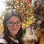Lorelai joined the competition — help win amazing prizes! woman, cat, glasses, christmas_tree, holiday_lights, decorations, indoor, smiling, festive, long_hair, feline, pet, holding, happy, portrait, celebration, warm_lighting, ornaments, cheerful, floor