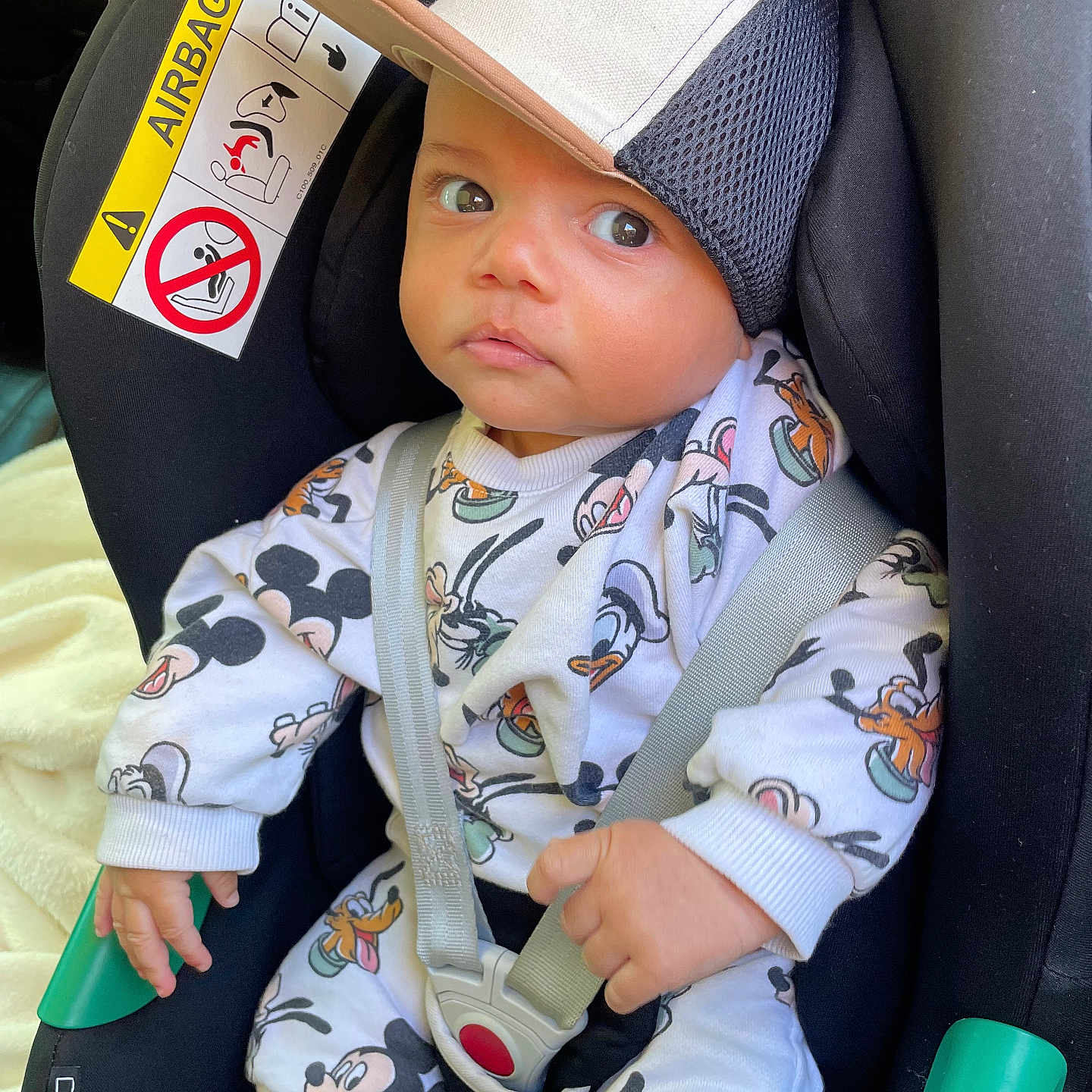 Sasha participe au concours pour gagner de l'argent avec cette photo : baby, child, car_seat, cap, mickey_mouse, clothing, seatbelt, infant, cute, portrait, person, sitting, indoors, seat, safety, straps, hat, cartoon_print, face, expression