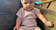 Paris joined the competition — help win amazing prizes! baby, infant, child, couch, headband, pajamas, purple, sock, furniture, indoor, table, smart_speaker, air_purifier, cozy, cute, portrait, seated, home, curious, living_room