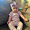 baby, infant, child, couch, headband, pajamas, purple, sock, furniture, indoor, table, smart_speaker, air_purifier, cozy, cute, portrait, seated, home, curious, living_room