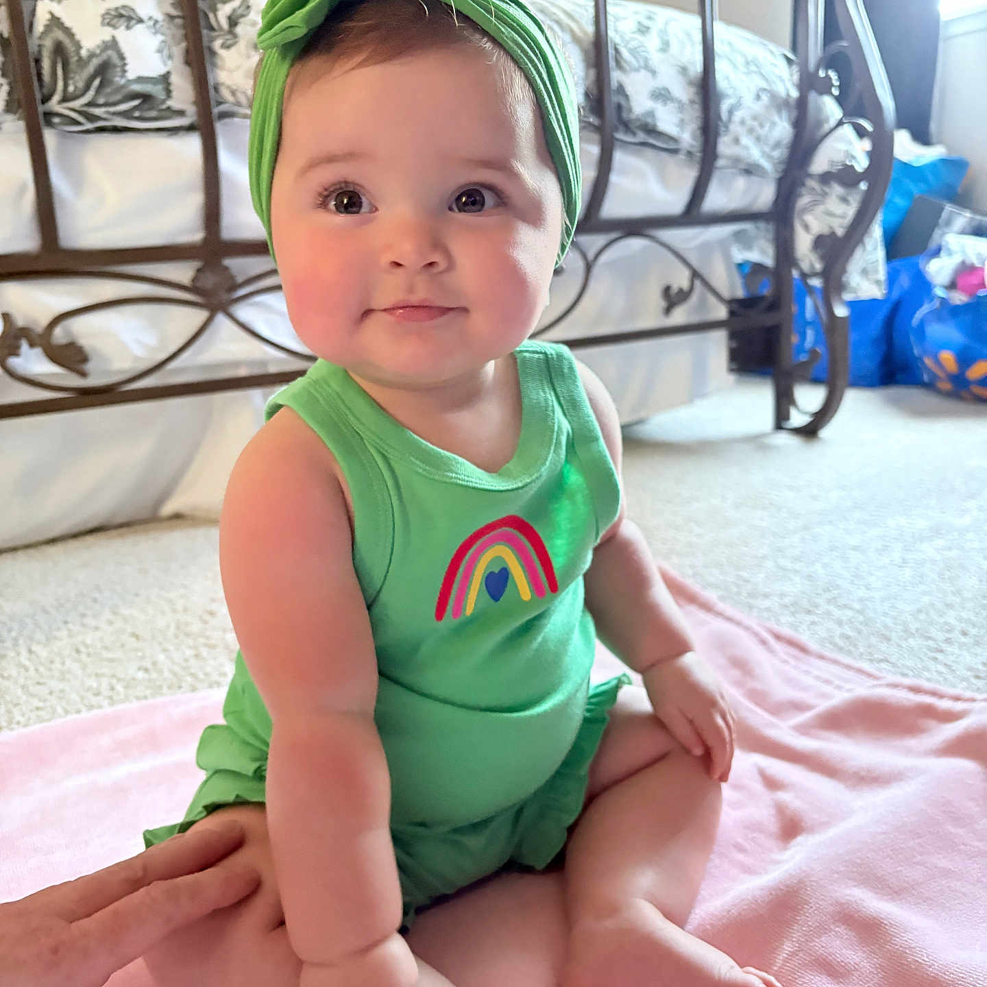 Paris joined the competition — help win amazing prizes! baby, child, infant, green_clothing, headband, sitting, pink_blanket, bedroom, carpet, metal_bed_frame, natural_light, cute, portrait, indoors, person, soft_light, happy, smiling, floor, hand