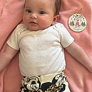 Paris joined the competition — help win amazing prizes! baby, infant, child, cute, pink_blanket, white_onesie, patterned_pants, mickey_mouse_print, christmas_ornament, holiday, holiday_decoration, face, portrait, curious, soft_texture, lying_down, rosy_cheeks, wide_eyes, indoor, adorable