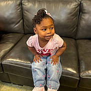 Nia is registered to the contest to win money with this photo: bow, candid, carpet, child, curly_hair, cute, fashion, girl, hands_on_knees, indoor, jeans, leather_sofa, living_room, pink_shirt, playful, portrait, sitting, smile, sneakers, toddler