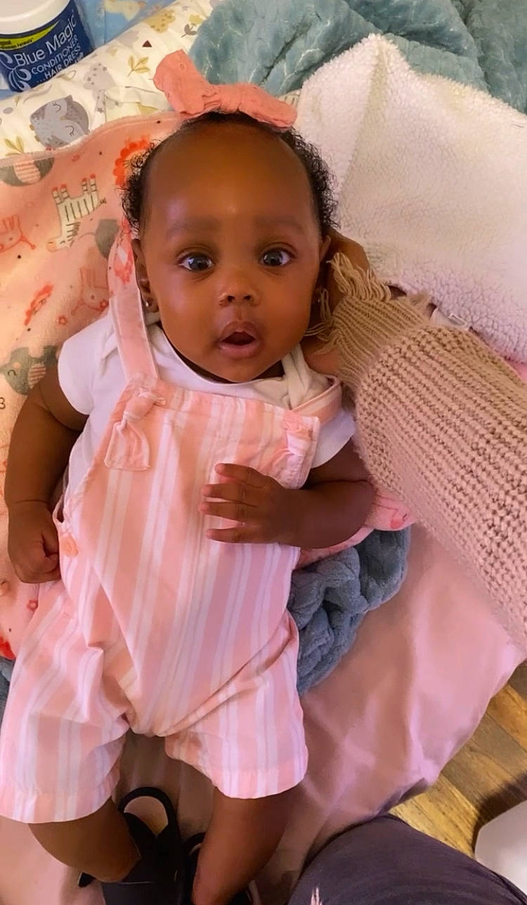 Honesty is registered to the contest to win money with this photo: baby, baby_toddler_clothing, cheek, comfort, dress, eye, eyelash, face, happy, head, human_body, linens, lip, neck, nose, person, pink, skin, sleeve, textile