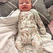 Ivy joined the competition — help win amazing prizes! baby, smile, onesie, bambi, blanket, pillow, bed, infant, clothing, cute, happy, lying_down, indoor, soft, child, person, comfort, cozy, newborn, sleepwear