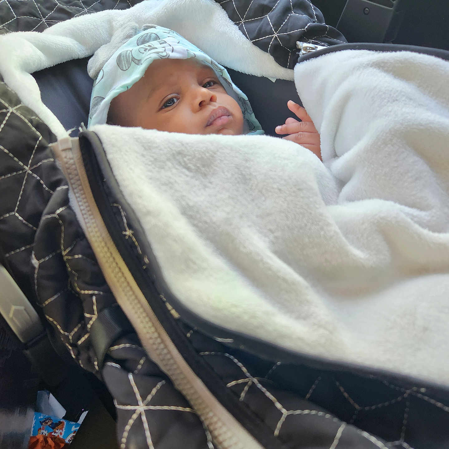 D'Marius joined the competition — help win amazing prizes! baby, blanket, car_seat, child, clothing, face, fleece, hood, infant, mickey_mouse, person, quilted, seat, soft, travel, vehicle_interior, white_blanket, wrapped, young_child, zipper