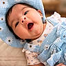 Layla joined the competition — help win amazing prizes! baby, infant, child, hat, blue, floral, clothing, cute, smiling, face, portrait, indoors, soft_light, bed, quilt, happy, skin, person, young, expression