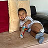Leo joined the competition — help win amazing prizes! toddler, child, couch, pillow, smile, indoor, sitting, clothing, white_shirt, candle, happy, feet, socks, face, person, relaxing, home, furniture, red_cushion, black_armrest