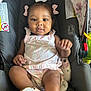 Noemi joined the competition — help win amazing prizes! baby, child, car_seat, pink_bows, pastel_clothing, face, portrait, infant, cute, sitting, soft_toys, safety_labels, indoors, smiling, young_child, footwear, legs, hand, head, black_hair