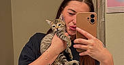 Joe is registered to the contest to win money with this photo: woman, cat, kitten, mirror, selfie, tattoo, bathroom, toilet, curtain, smartphone, black_tshirt, tabby_cat, young_adult, pouting, holding, indoor, reflection, casual, furniture, wooden_stool