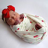 Chevelle joined the competition — help win amazing prizes! baby, blanket, cherry_pattern, closeup, comfort, cute, headband, indoors, infant, newborn, peaceful, portrait, red_bow, resting, sleeping, soft, tiny_feet, tiny_hands, white_background, wrapped
