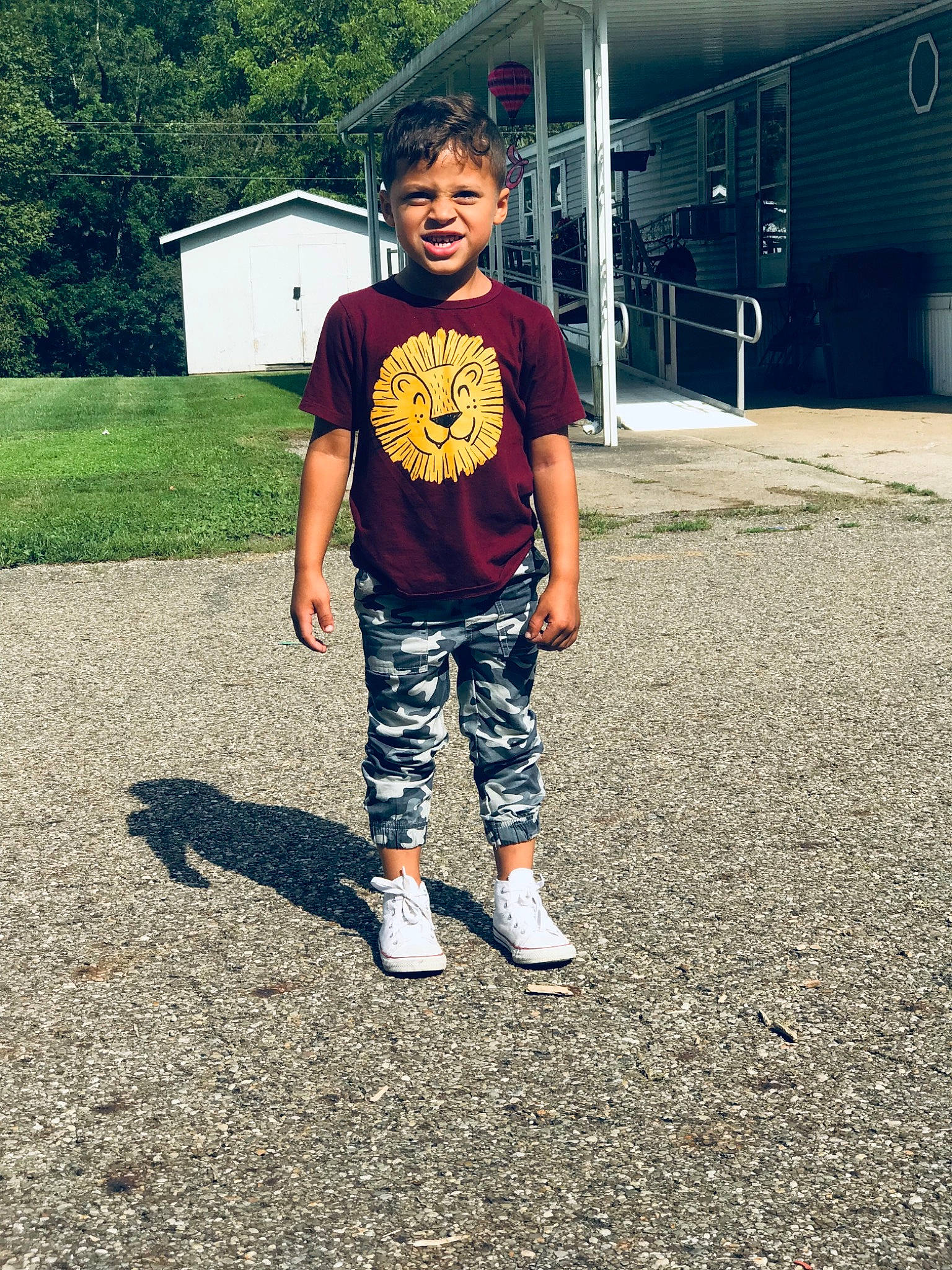 Dominic is registered to the contest to win money with this photo: asphalt, denim, electric_blue, grass, happy, knee, leisure, pattern, person, plant, recreation, road_surface, sleeve, sneakers, sportswear, street_fashion, t_shirt, tints_and_shades, toddler, tree