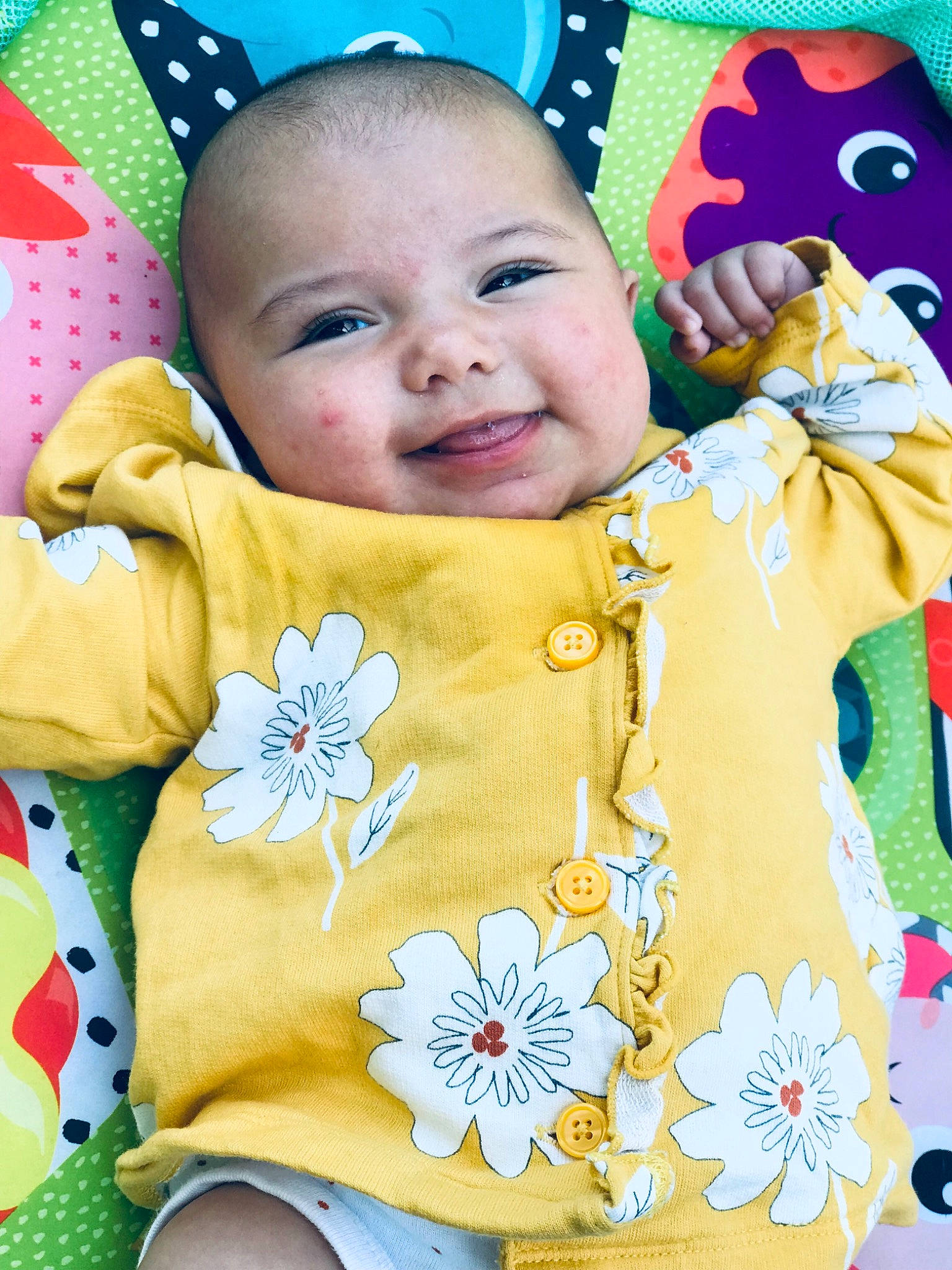Amaya is registered to the contest to win money with this photo: baby, baby_toddler_clothing, cheek, eye, face, facial_expression, flower, green, happy, head, joy, orange, person, pink, product, skin, sleeve, smile, textile, toddler