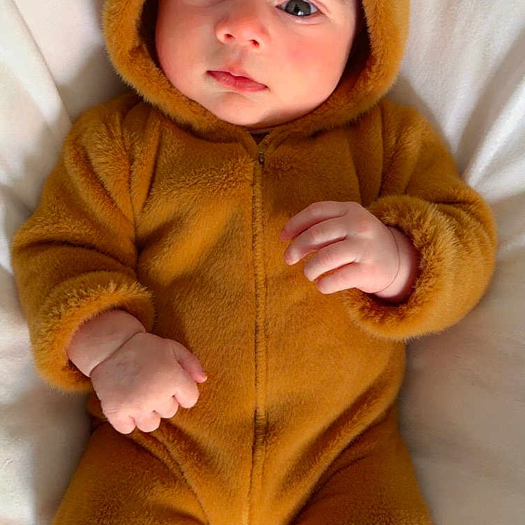 Musfirah is registered to the contest to win money with this photo: adorable, baby, bear_costume, blanket, child, closeup, cozy, cute, ears, expression, feet, fuzzy_suit, hands, hood, indoors, infant, portrait, sleepwear, soft_texture, warm