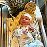 Brooks joined the competition — help win amazing prizes! newborn, baby, infant, hospital_bassinet, blanket, onesie, hat, dinosaur_pattern, wooden_sign, baby_clothing, sleepwear, smile, person, indoors, crib, cute, resting, fresh_born, baby_bed, soft_texture