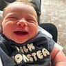 Brooks is registered to the contest to win money with this photo: baby, newborn, smiling, infant, clothing, shirt, milk_monster, arms, person, happy, face, head, skin, hand, indoor, floor, tile, furniture, comfort, closeup