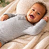 baby, blanket, child, comfort, cozy, curly_hair, cute, expression, face, happy, indoors, infant, lying_down, onesie, portrait, relaxed, skin, smiling, soft, warm