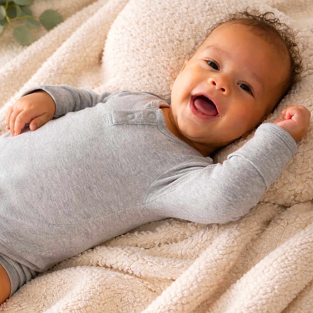 Zaya joined the competition — help win amazing prizes! baby, smiling, infant, blanket, cozy, onesie, happy, cute, portrait, child, lying_down, soft, warm, curly_hair, skin, face, indoors, comfort, relaxed, expression