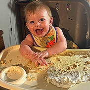 Arthur joined the competition — help win amazing prizes! baby, high_chair, food, messy, smiling, bib, cake, hands, face, happy, indoor, child, eating, table, cream, kitchen, person, young_child, fun, playful