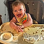 baby, high_chair, food, messy, smiling, bib, cake, hands, face, happy, indoor, child, eating, table, cream, kitchen, person, young_child, fun, playful