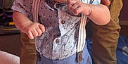 Konrad is registered to the contest to win money with this photo: adult, baby, bed, blue, child, clothing, curious, expression, foot, hand, indoor, mattress, pattern, person, shirt, skin, standing, support, suspenders, tattoo