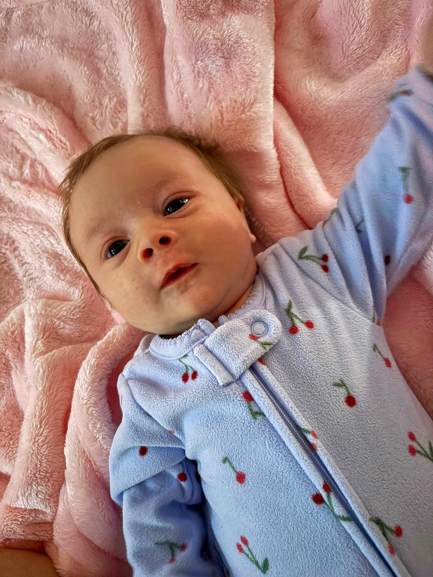 Aurora is registered to the contest to win money with this photo: baby, infant, blanket, blue_onesie, cherry_pattern, soft_texture, cute, lying_down, child, face, expression, skin, head, clothing, newborn, sleepwear, comfort, warm, indoor, portrait