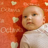 baby, infant, face, portrait, closeup, child, blanket, heart, text, name, pink, clothing, soft_texture, cute, skin, person, young, lying_down, expression, indoor