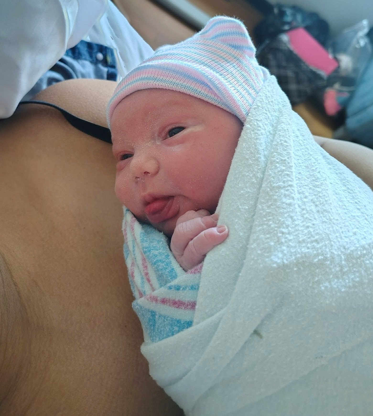 Octavia is registered to the contest to win money with this photo: newborn, baby, swaddle, blanket, striped_hat, hospital, maternity, infant, tongue_out, closeup, face, skin, tiny_hand, parent_chest, cozy, hospital_room, postpartum, portrait, soft_towel, peaceful