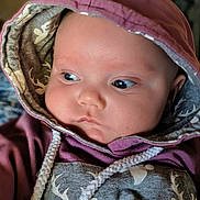 Octavia is registered to the contest to win money with this photo: baby, hoodie, child, face, portrait, clothing, cute, infant, expression, looking_away, soft_lighting, indoors, young_child, warm_colors, cozy, deer_pattern, closeup, headwear, rope_string, apparel