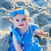 Claire joined the competition — help win amazing prizes! baby, child, blue_dress, headband, bow, sand, beach, smile, face, cute, sunlight, outdoor, sitting, happy, infant, person, skin, eyes, portrait, summer