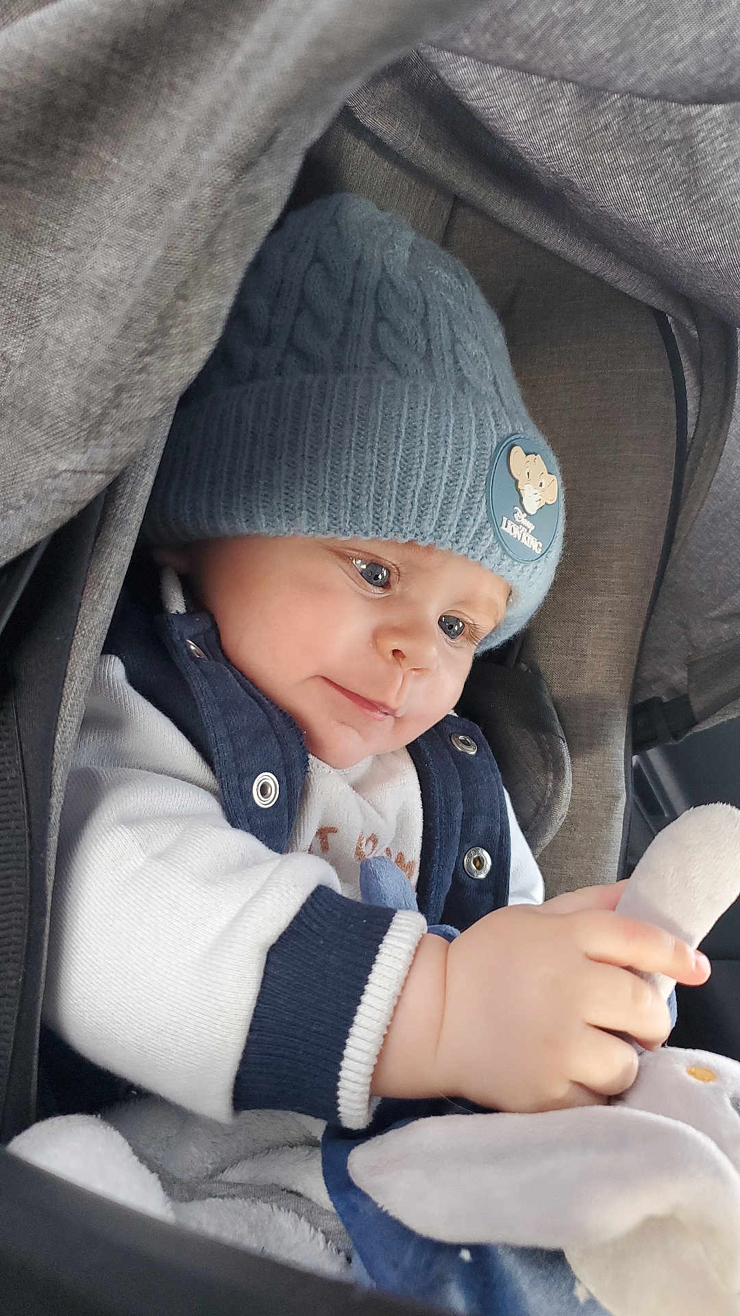 Mathis a rejoint le concours — aidez-le/la à gagner de superbes lots ! baby, child, blue_hat, knit_hat, lion_king, plush_toy, car_seat, blanket, coat, sweater, cute, infant, warm_clothing, hands, face, portrait, indoor, soft_toy, close_up, winter_wear