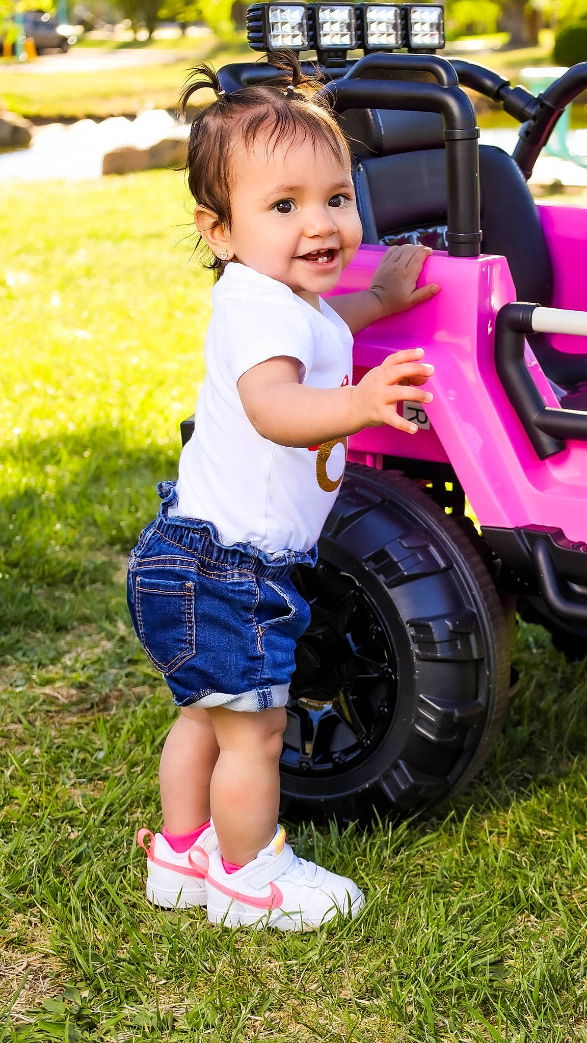 Yesenia joined the competition — help win amazing prizes! automotive_tire, baby_toddler_clothing, face, facial_expression, grass, green, happy, joy, leg, motor_vehicle, people_in_nature, person, photograph, plant, riding_toy, shorts, smile, summer, tartan, tire