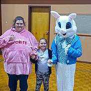 Rose is registered to the contest to win money with this photo: child, adult, mascot, easter_bunny, costume, gymnasium, wooden_floor, holding_hands, pink_hoodie, leggings, sneakers, smiling, indoor, door, wall, person, group, casual_clothing, happy, photography