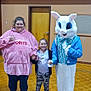 child, adult, mascot, easter_bunny, costume, gymnasium, wooden_floor, holding_hands, pink_hoodie, leggings, sneakers, smiling, indoor, door, wall, person, group, casual_clothing, happy, photography