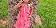 Natalee is registered to the contest to win money with this photo: child, girl, tree, grass, pink_dress, polka_dot, sneakers, outdoor, nature, playful, peace_sign, casual, portrait, person, summer, greenery, young, fashion, cute, park