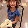 Natalee is registered to the contest to win money with this photo: child, girl, smiling, snake, pet, chair, blue_shirt, shorts, indoor, floor, person, animal, reptile, young, cute, happy, brown_hair, holding, seated, casual_clothing