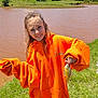 child, girl, fish, fishing, hoodie, orange_clothing, outdoor, pond, water, grass, smile, happy, nature, sunlight, portrait, casual, wind, small_fish, recreation, daytime