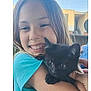 Madalynn is registered to the contest to win money with this photo: child, smiling, kitten, black_cat, hugging, outdoor, blue_shirt, pet, happy, animal, face, person, young, cute, building, sunny, daylight, portrait, holding, friendship
