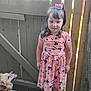 child, girl, dog, pet, pink_dress, minnie_mouse, sunflower_pattern, hair_bow, outdoor, fence, wood, happy, smiling, animal, tongue_out, cute, portrait, standing, playful, daylight