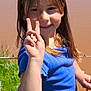 Bayleigh is registered to the contest to win money with this photo: child, girl, peace_sign, smiling, blue_shirt, outdoor, nature, greenery, water, sunlight, happy, portrait, long_hair, casual_clothing, person, young, summer, grass, daylight, fun