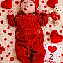 baby, red_overalls, red_hat, valentines_day, hearts, teddy_bear, milestone_card, fluffy_blanket, cute, infant, love, heart_shapes, lying_down, celebration, adorable, portrait, soft_texture, holiday_theme, child, smiling_face