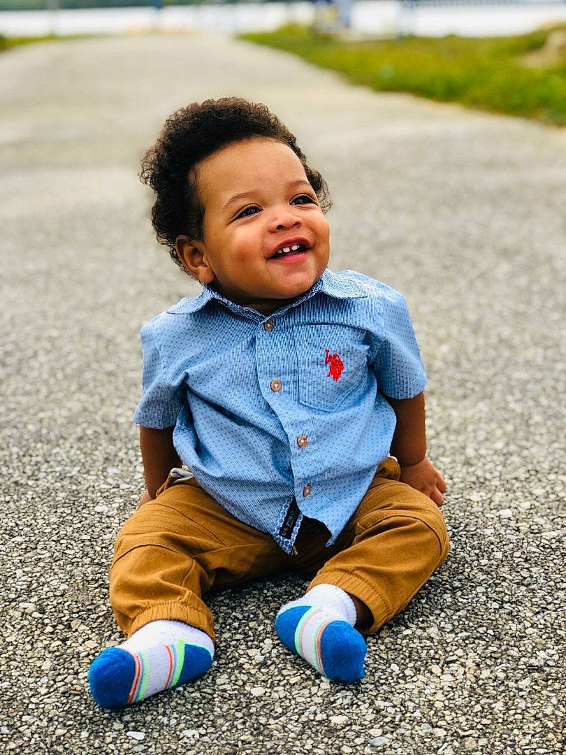 Marcellus is registered to the contest to win money with this photo: baby, blue, cheek, child, facial_expression, grass, happy, head, jeans, outerwear, people, person, photography, plant, play, portrait_photography, sitting, smile, toddler, vacation