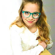 Kylliana a rejoint le concours — aidez-le/la à gagner de superbes lots ! blue_eyes, casual, child, cute, desk, face, girl, glasses, happy, indoor, long_hair, person, portrait, sitting, smile, vest, wavy_hair, white_clothing, wood, young