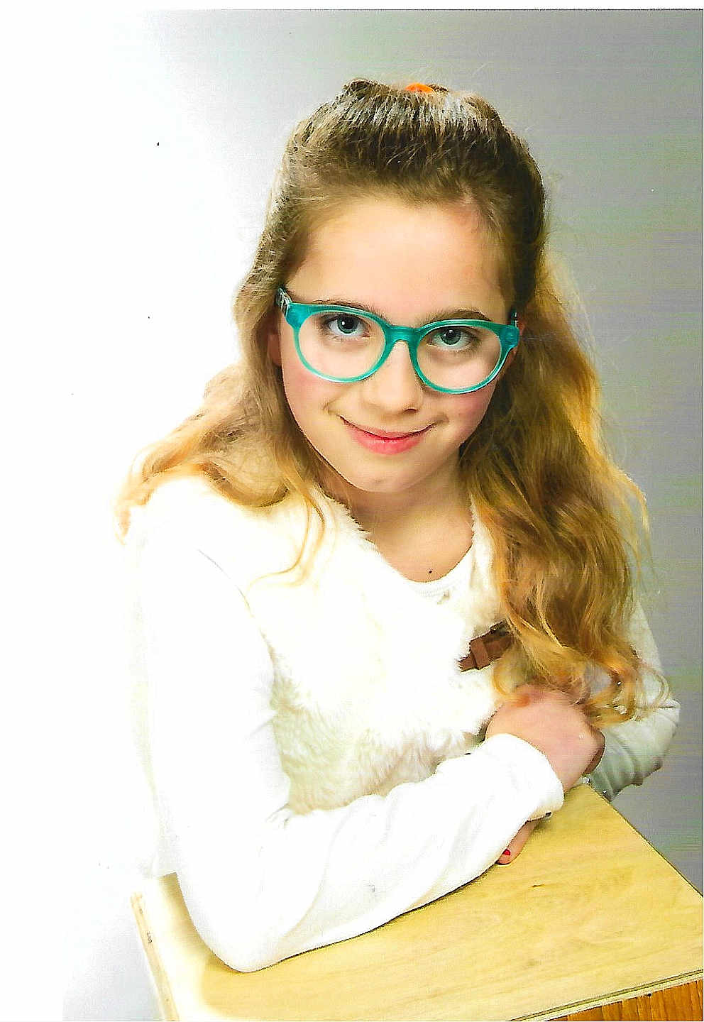 Kylliana a rejoint le concours — aidez-le/la à gagner de superbes lots ! blue_eyes, casual, child, cute, desk, face, girl, glasses, happy, indoor, long_hair, person, portrait, sitting, smile, vest, wavy_hair, white_clothing, wood, young