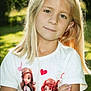 arms_crossed, blonde_hair, cartoon_characters, casual_clothing, child, cute, daylight, face, greenery, happy, heart, nature, outdoor, person, portrait, smile, standing, sunlight, tshirt, young_girl