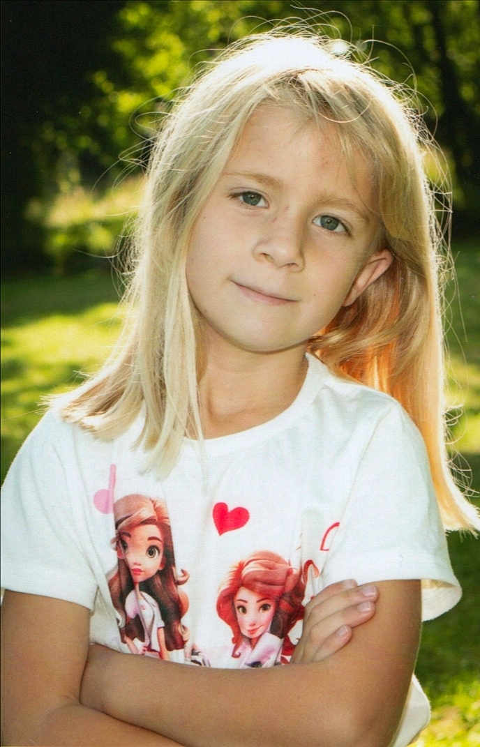 Elyna a rejoint le concours — aidez-le/la à gagner de superbes lots ! arms_crossed, blonde_hair, cartoon_characters, casual_clothing, child, cute, daylight, face, greenery, happy, heart, nature, outdoor, person, portrait, smile, standing, sunlight, tshirt, young_girl