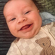 Louie joined the competition — help win amazing prizes! baby, smiling, face, onesie, teddy_bear, clothing, blanket, closeup, infant, cute, child, happy, portrait, skin, expression, young, lying_down, cozy, soft, texture