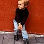 Célyan participe au concours pour gagner de l'argent avec cette photo : child, boy, portrait, black_sweater, blue_jeans, black_boots, standing, pavement, orange_wall, outdoor, cute, fashion, casual, young, smiling, hair, clothing, person, urban, playful